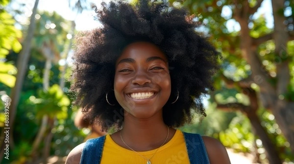 Fototapeta   Close-up of a person in a yellow shirt, wearing a necklace and smiling, with a tree in the background