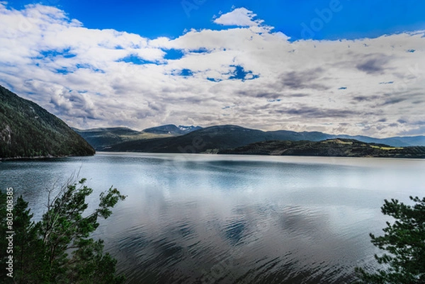 Fototapeta Serene view over Tingvollfjorden in Norway, featuring calm waters with reflections under a blue summer cloud sky.