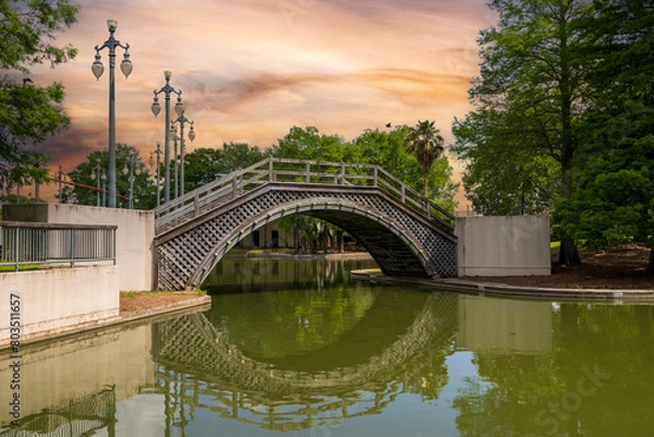 Obraz a gorgeous spring landscape at Louis Armstrong Park with lush green trees, plants and grass, a lake and powerful  clouds at sunset in New Orleans Louisiana USA