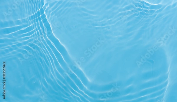Fototapeta Blue water with ripples on the surface. Defocus blurred transparent blue colored clear calm water surface texture with splashes and bubbles. Water waves with shining pattern texture background.