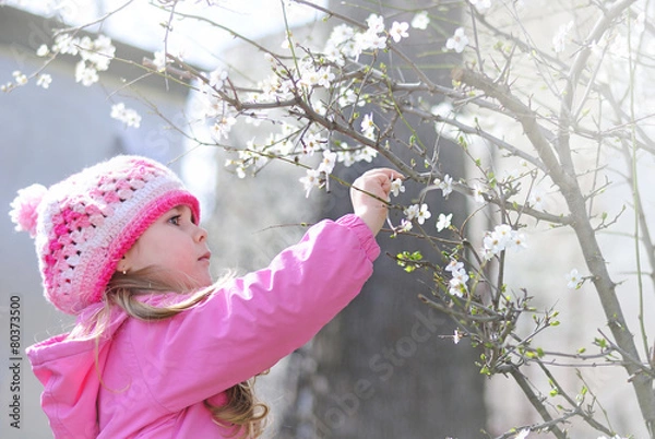 Obraz beautiful little girl near a flowering tree