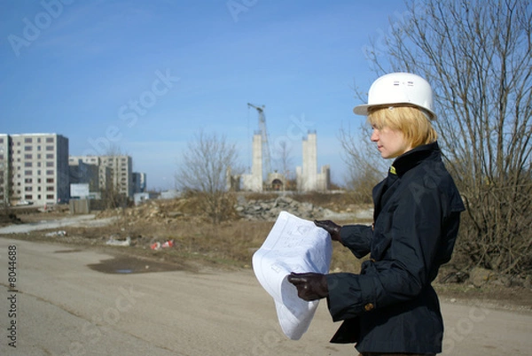 Fototapeta women architect with blueprints and hard hat at site