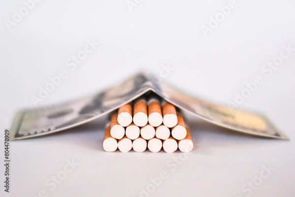 Obraz Smoking concept cigarettes on dollar background Cigarettes scattered on dollars.