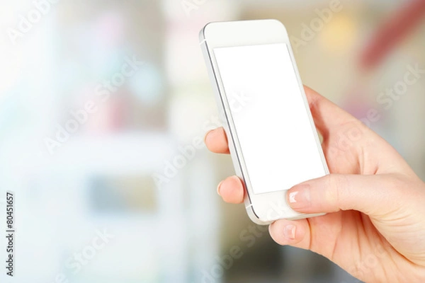 Fototapeta Hand holding smart phone on bright background