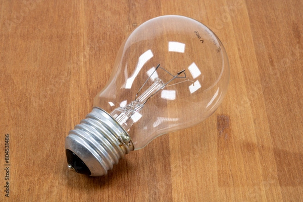 Fototapeta A light bulb on wooden desk