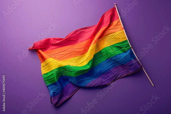 Fototapeta A rainbow flag is displayed on a purple background. The flag is colorful and vibrant, representing the LGBTQ+ community