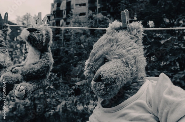 Obraz children's toys hang on a rope against the background of destroyed burnt houses in Ukraine