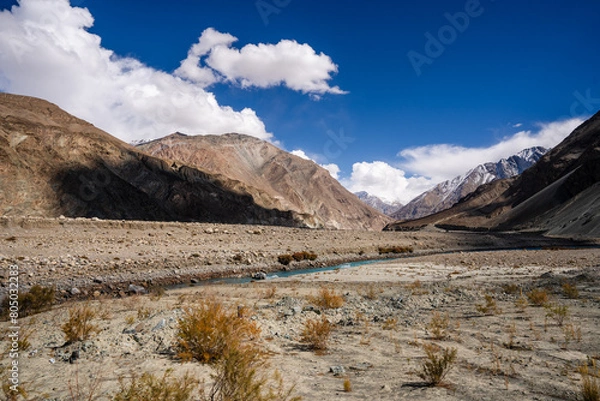 Fototapeta Vibrant view of the Indus River flowing through a barren Himalayan valley under a clear blue sky in Ladakh, India.