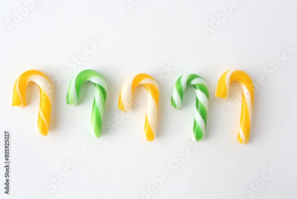 Obraz Christmas candies in yellow and green on a white background. New Year concept.Candies in the form of Santa's staff.