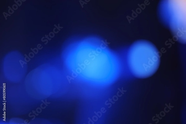 Fototapeta Abstract image with soft undefined shapes of blue color and blurry lights like those of a music concert stage. Dark background.