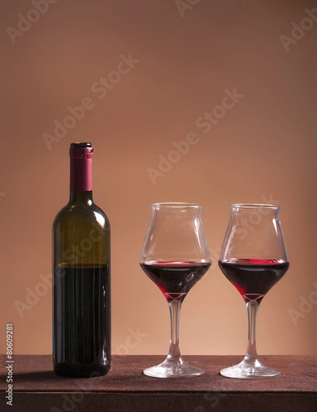 Fototapeta Red wine bottle and two filled wineglasses