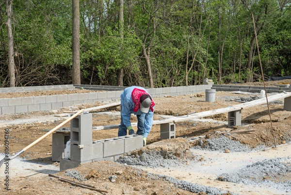 Obraz Migrant Worker Laying Cement Block Building Foundation