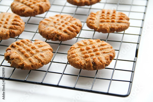 Fototapeta Process of making peanut butter cookies.  Peanut butter cookies are cooling after baking on a rack on a white background.