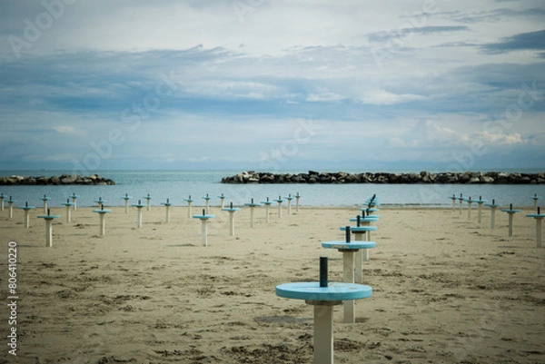 Fototapeta Romagna or Riviera Romagnola beach, off season mood. Before season starts in april or may, or october. Liminal spaces, slight melancholy feeling, uncertain weather, damp sand.