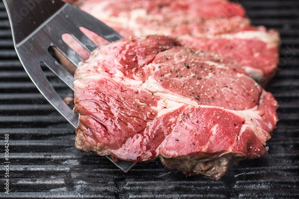 Fototapeta Beef steaks on grill or BBQ with spatula