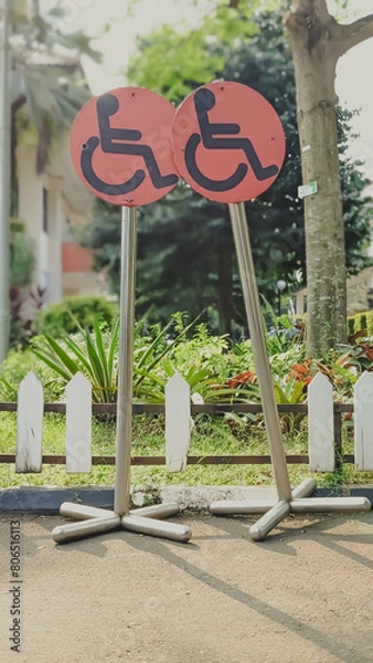 Obraz Low angle view of car parking sign posts intended for disabled people near the public garden. The implementing concept of human rights equality