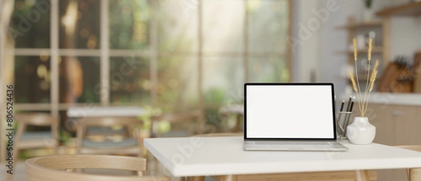 Fototapeta An opened laptop computer on a table in cozy contemporary coffee shop or restaurant.