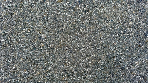 Fototapeta Closeup view  of a compact gravel road surface, showcasing a detailed texture of interlocked stones in a durable, gritty layout.