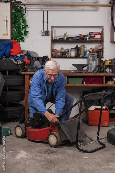 Fototapeta Senior worker with lawn mower in workshop