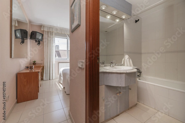 Obraz Bathroom of a house with furniture with marble countertop and white porcelain sink with integrated beveled mirror in the bedroom anteroom