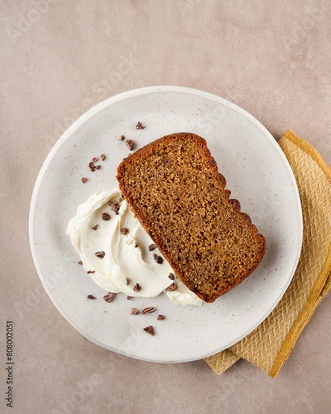 Obraz Cake slice topped with whipped cream on a cream background, with copy space. Top view. Close Up. Birthday loaf cake concept.