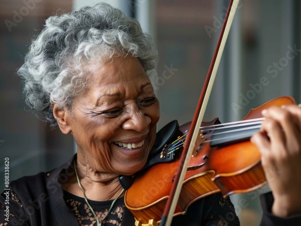 Fototapeta Closeup portrait os a senior black woman playing the violin with a smile.  Shallow dof.