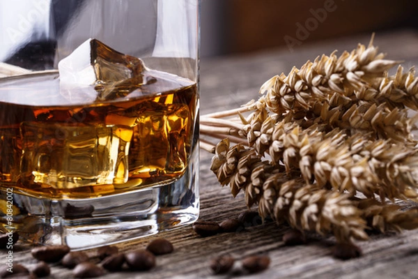 Fototapeta Kieliszek whisky z lodem i pszenicą na drewnianym stole.