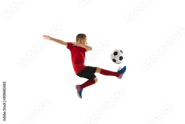 Obraz Dynamic photo of junior football player kicking ball against white studio background. Mid-air pass in motion. Concept of professional sport, championship, youth league, hobby. Ad