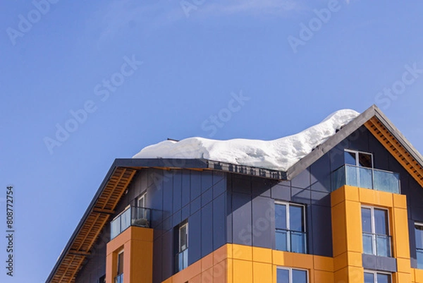 Fototapeta Dangerous snow falls from the roofs of the buildings. Winter with heavy snowfall. Snow falls above sidewalks with people. Uncleaned snow
