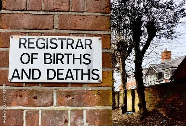 Fototapeta A closeup of a sign for the Registrar of Births and Deaths on a brick wall in the UK. 