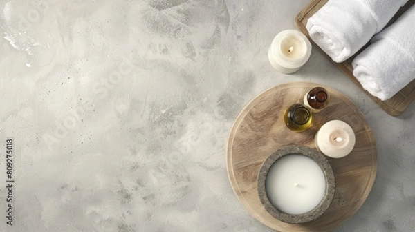 Fototapeta Spa essentials on a tray on a light textured background. Candles, towels, and essential oil set for relaxation. Concept of spa treatment, wellness, and serene decor. Banner. Copy space
