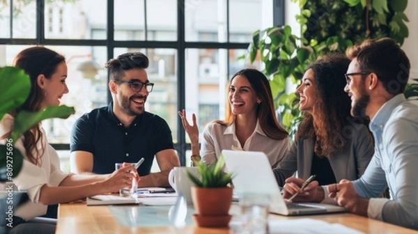 Fototapeta A group of five business professionals are sitting around a table having a meeting