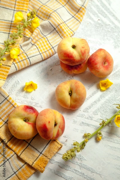 Fototapeta Several whole saturn peaches or flat peach on white wooden background..