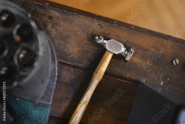 Fototapeta Flat lay view of the goldsmith's hammer and six spline ring stretcher and reducer lying on the workshop table.
