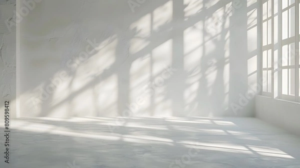 Fototapeta Spacious empty room with large windows casting dramatic shadows and sunlight across a smooth floor.