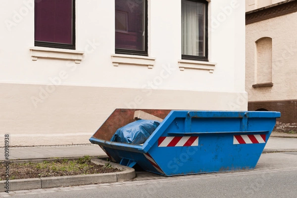 Obraz Ein blauer Container für Abfall steht vor einem Wohnhaus