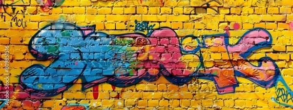 Fototapeta Colorful graffiti text on a yellow brick wall background. The graffiti is in the style of colorful street art.