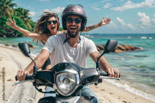 Fototapeta Happy couple riding a scooter on vacation, having fun and celebrating while driving through a tropical island with palm trees in the background