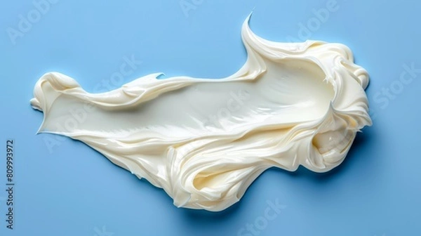 Fototapeta   A detailed view of a bluish background bearing a mound of creamy substance, with a solitary droplet of water poised above its center