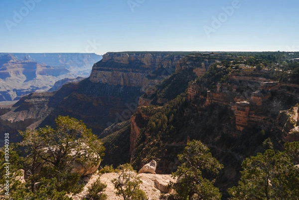 Fototapeta Explore breathtaking panoramic view of Grand Canyon under clear blue skies. Vast geological landscape showcases red and brown rock formations in Arizona, USA.