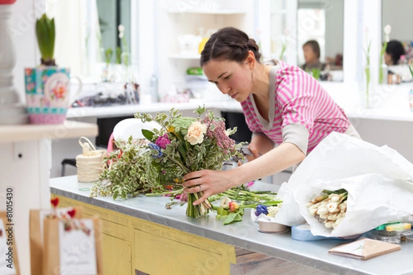 Fototapeta Masterclass of smiling florist at work with bunch of flowers