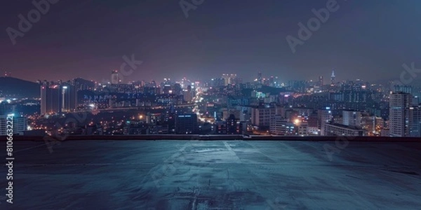 Fototapeta A city skyline at night with a dark sky and a few clouds