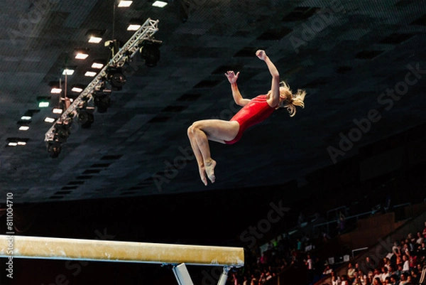 Obraz exercise on balance beam gymnastics, female gymnast perform backward somersault landing on floor