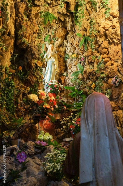 Fototapeta 植物に囲まれた像に祈りをささげる人の像