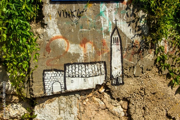Fototapeta Drawing of a castle in black and white paint on a concrete wall covered with green ivy. Graffiti