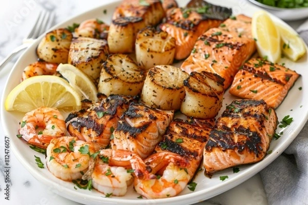 Fototapeta A platter of grilled seafood including shrimp, scallops, and salmon, served with lemon wedges