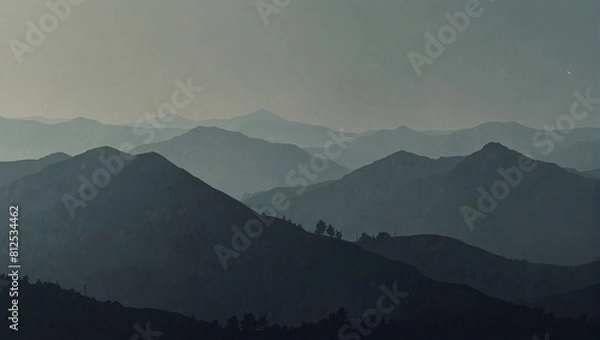Obraz A black and white photo of a mountain range in the distance with a hazy sky.