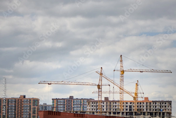 Fototapeta Group of tower crane on construction site. Tall buildings under construction. Real estate construction. Concept of urban development and architecture.