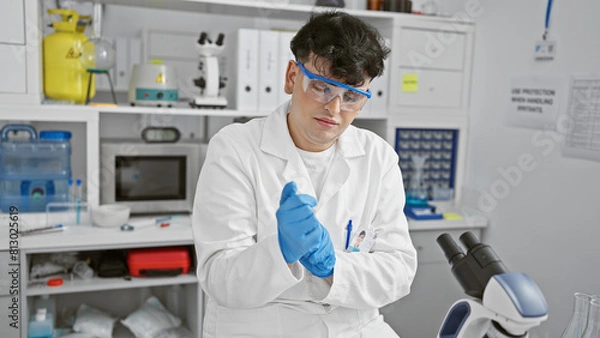 Fototapeta A young man in a lab coat performs a scientific experiment indoors, exuding professionalism and focus.
