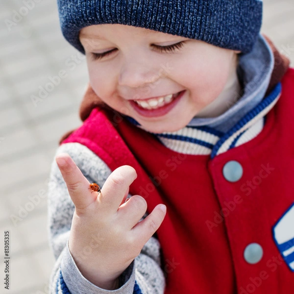 Fototapeta Toddler smiling child looking at a ladybug